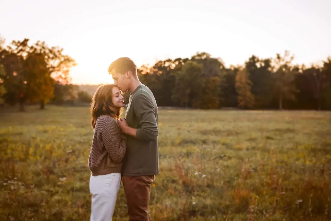 A couple close together in a field at last light