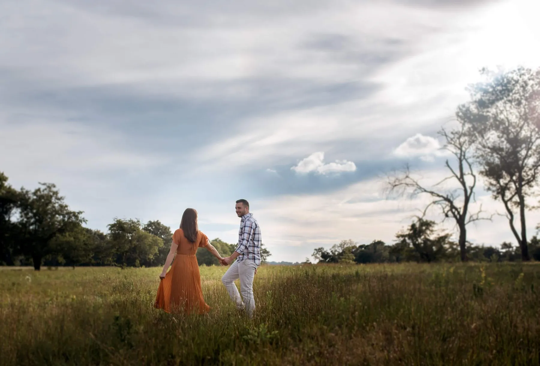 A couple standing together in an open field under a wide sky