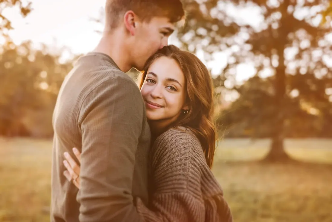 A couple backlit by low sun beneath a large tree