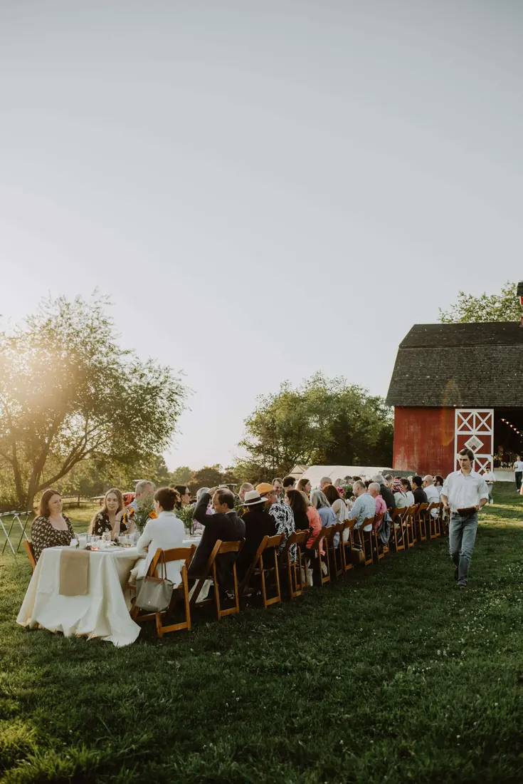 A long table dinner in a field at golden hour