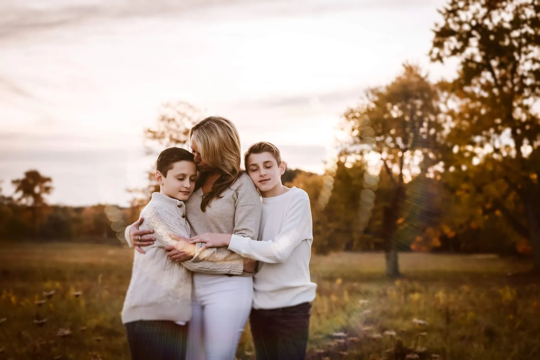 A mother and her two sons holding each other at golden hour