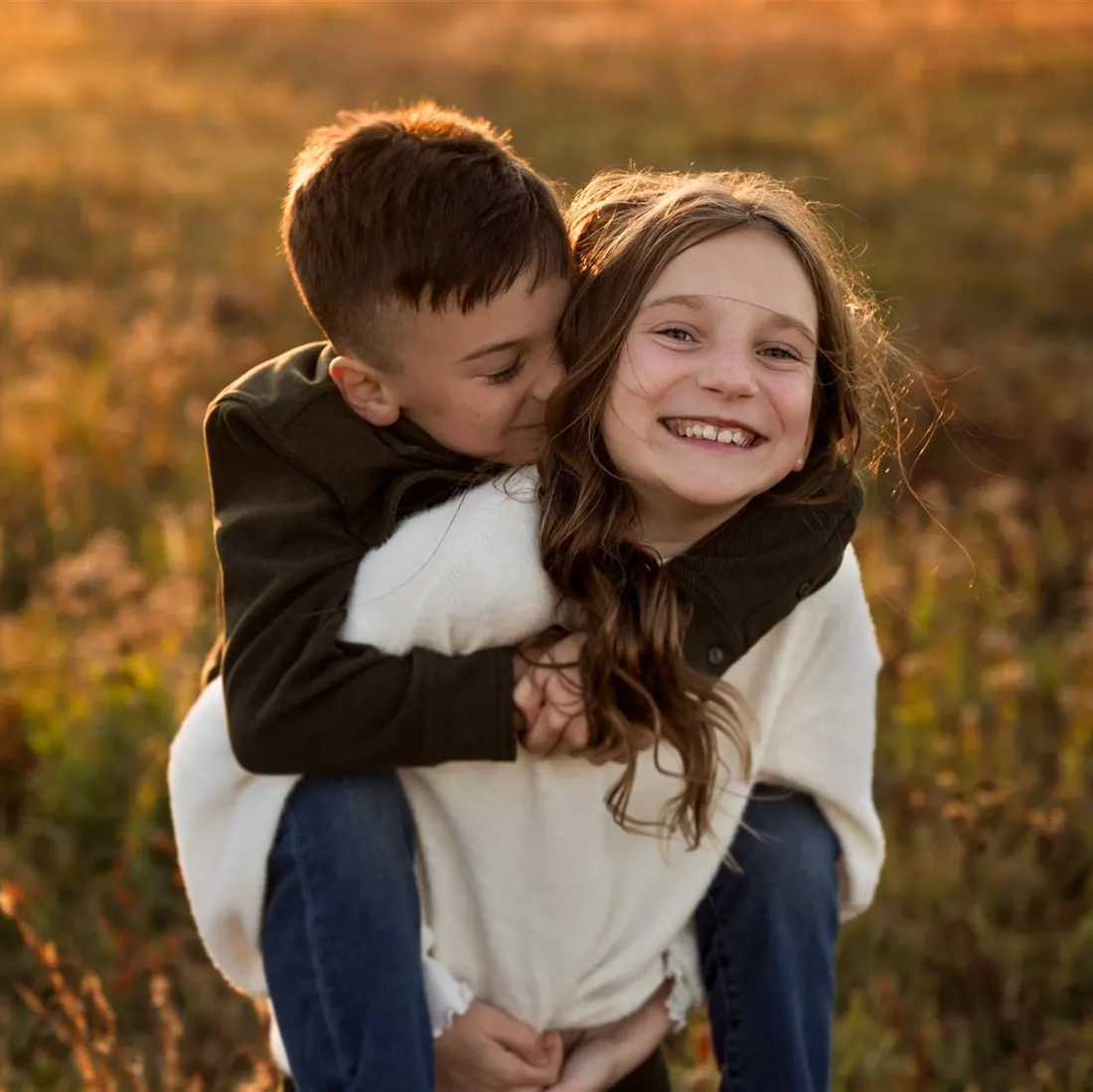 A brother hugging his sister in a golden autumn field