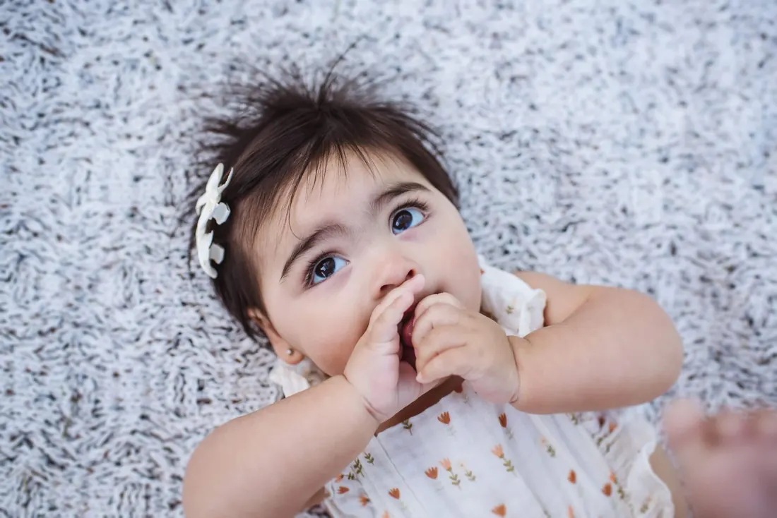 A baby lying on a blanket looking up at the camera
