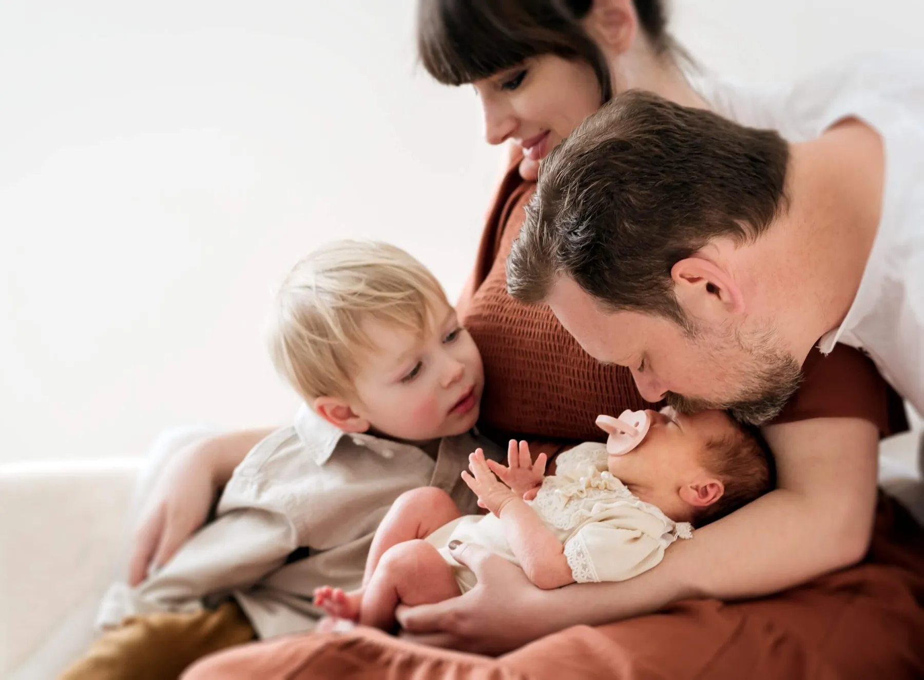 Parents and a toddler leaning in around a sleeping newborn
