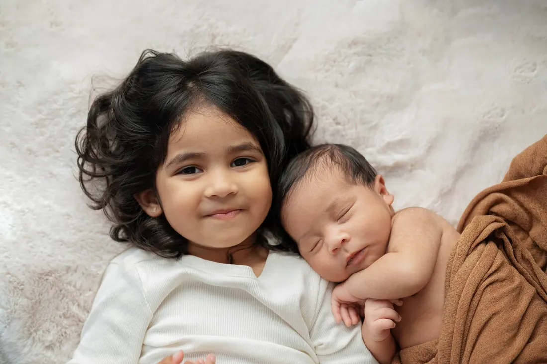 A big sister lying beside her sleeping newborn brother
