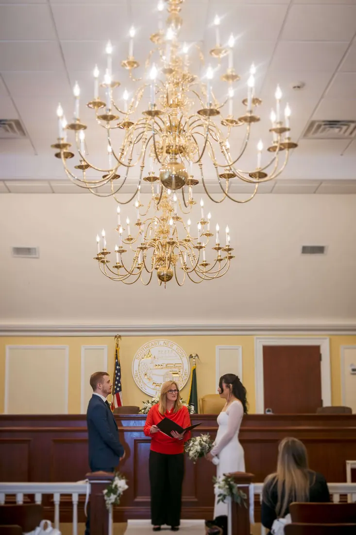 A ceremony beneath a chandelier in a historic hall