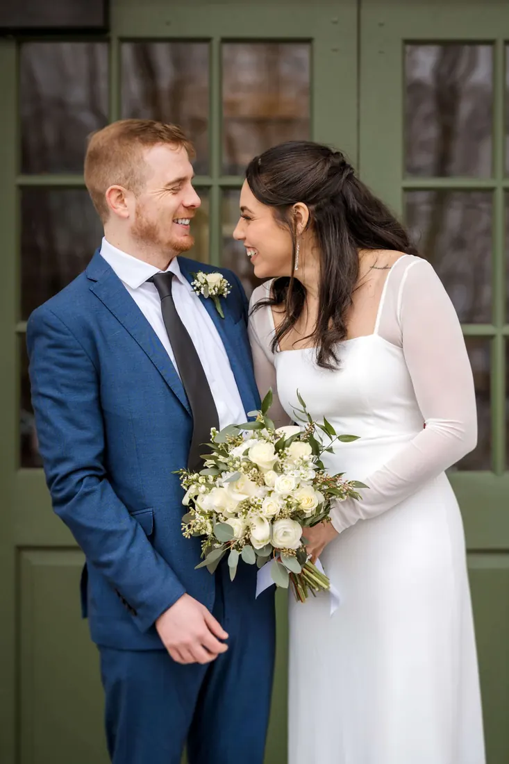 A couple portrait in front of green wooden doors